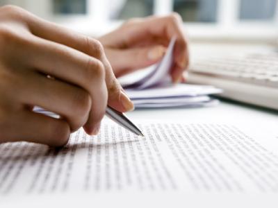 Close up of printed text being reviewed by someone with a pen in hand.