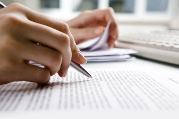 Close up of printed text being reviewed by someone with a pen in hand.