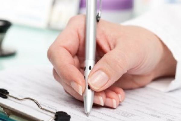 a close up of a nurse's hand writing out a prescription 